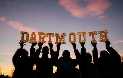 Silhouettes of students holding up letters that spell &quot;Dartmouth&quot; around sunset.